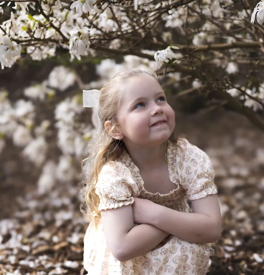Young girl looking up at blossom trees during a spring family session